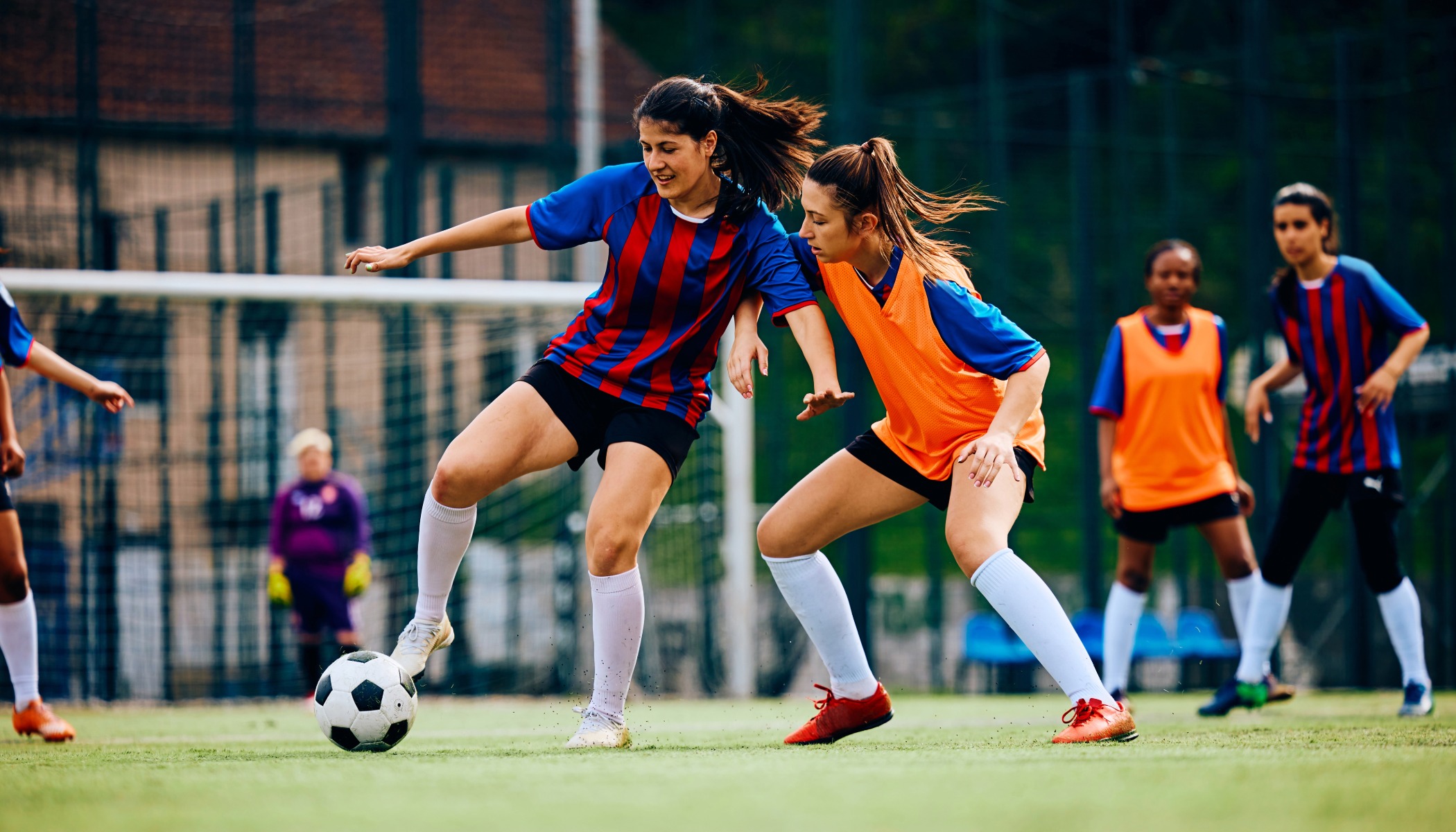 Womens soccer league match with adult players on an outdoor grass pitch